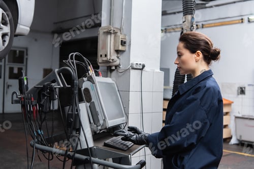 Preview: Side view of forewoman using computer near blurred car in garage