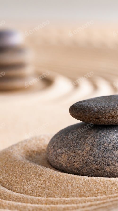 Preview: Stacked stones on sand with ripples in a zen garden during daylight hours