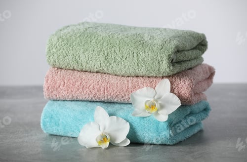 Preview: Stacked soft colorful towels with flowers on grey table