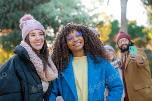 Preview: Happy friends from diverse cultures and races taking selfie looking at camera smiling outdoors.