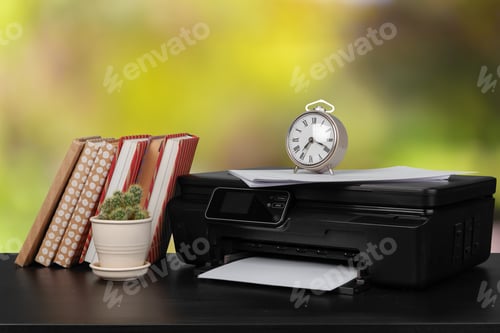Preview: Stack of books and home printer against blurred background
