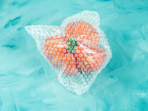 Preview: Tomato in plastic package on turquoise