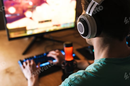 Preview: Image of focused man in headphones playing video game on computer