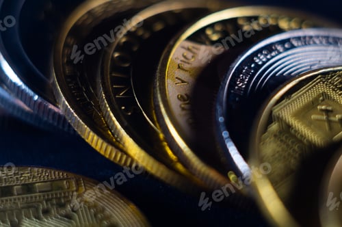 Preview: Closeup shot of gold and silver coins scattered on a surface illuminated with bright light