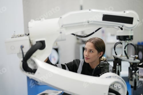 Preview: Female technician programs a robot arm with a digital tablet and assembly robot in a factory