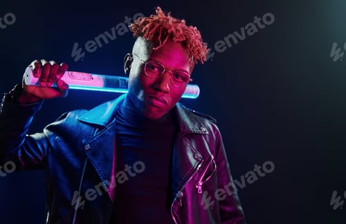 Preview: Futuristic neon lighting. Young african american man in glasses standing in studio