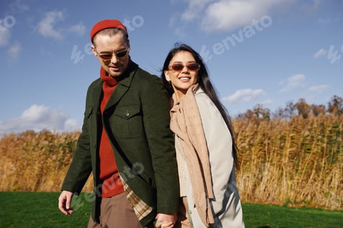 Preview: A loving couple enjoying a cozy autumn stroll in stylish warm attire under a blue sky