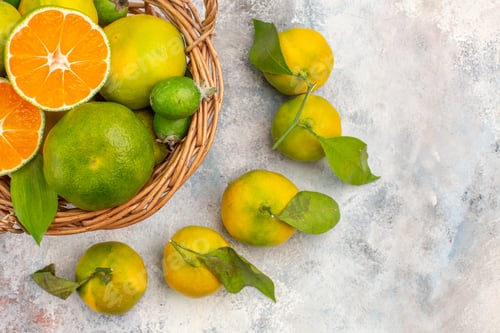 Preview: top close view fresh mandarines in wicker basket surrounded by mandarines on nude background free