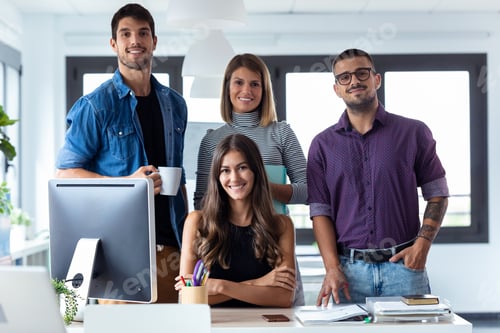Preview: Successful business team posing grouped around an attractive young woman looking at the camera