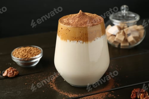 Preview: Delicious dalgona coffee in glass, granules, walnuts and brown sugar on wooden table, closeup