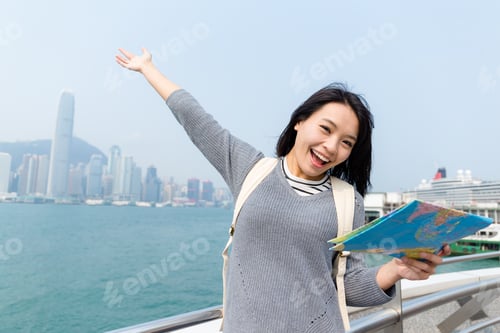 Preview: Excited woman holding a map in Hong Kong