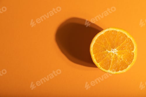 Preview: Ripe cut orange on orange pastel background. Top view, copy space, hard light.