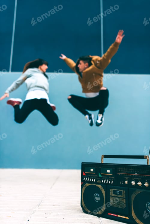 Preview: Young happy couple dancing on the street with a vintage radio cassette stereo