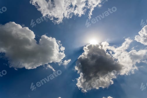 Preview: Rays of sun shining through white puffy clouds and blue sky