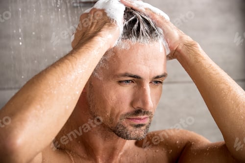 Preview: close up portrait of adult man washing hair with shampoo and taking shower