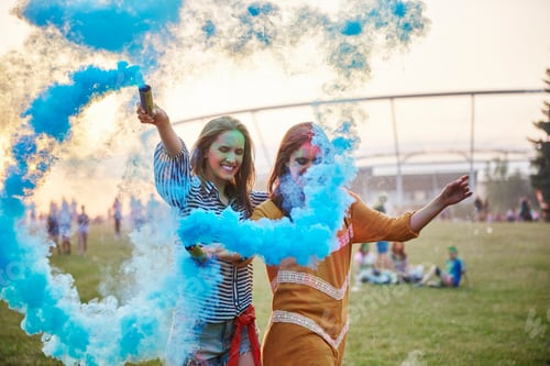 Preview: Two young women dancing with blue smoke bombs at Holi Festival