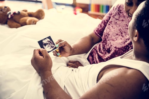 Preview: Black couple looking at baby ultrasound scan photo
