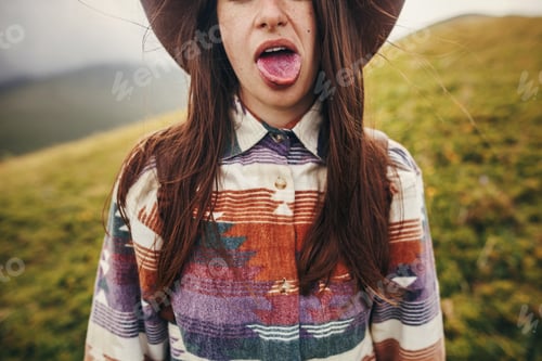 Preview: Girl showing colored blue tongue from eating blueberries in sunny mountains