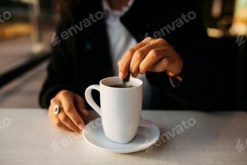 Preview: Businesswoman stirring hot beverage in a cafe during business trip
