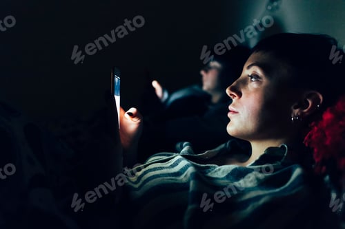 Preview: Women in bed in darkness using mobile phones