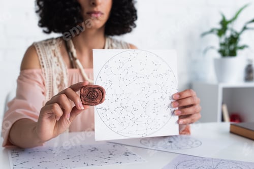Preview: partial view of oracle holding clay rune and constellations map