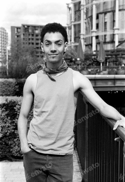 Preview: Young man posing in urban setting, wearing tank top and bandana, grainy monochrome film photography