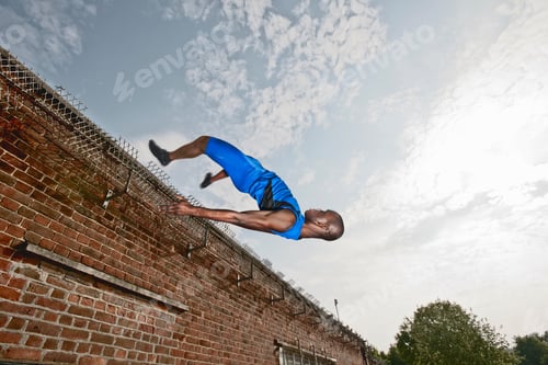 Preview: Athlete vaulting over brick wall