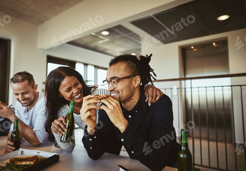 Preview: Laughing coworkers drinking beers and eating pizza after work