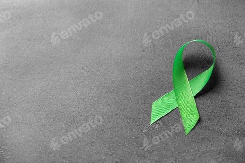 Preview: Green ribbon on grey background. Cancer awareness