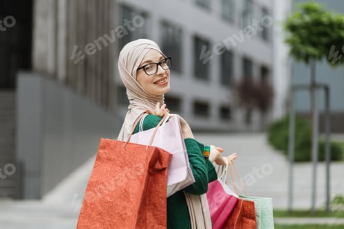 Preview: Muslim woman, wearing casual clothes, going for shopping in background of modern city buildings.