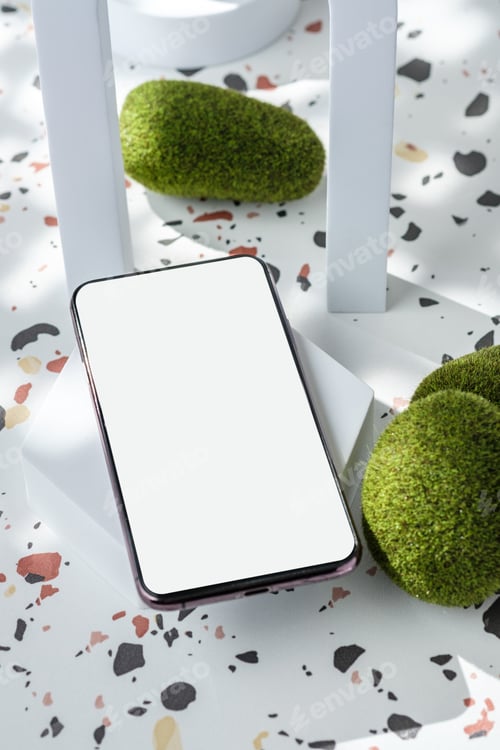 Preview: mobile phone on white geometric pedestal on terrazzo background with summer sunlight and moss rock