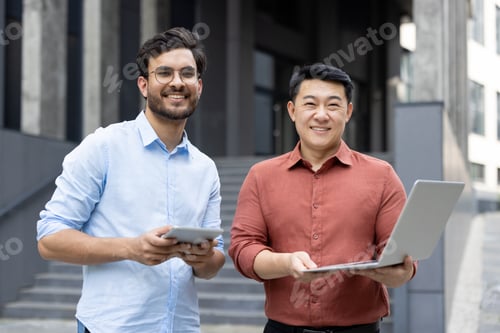 Preview: Two professionals using digital devices outdoors in a modern business setting