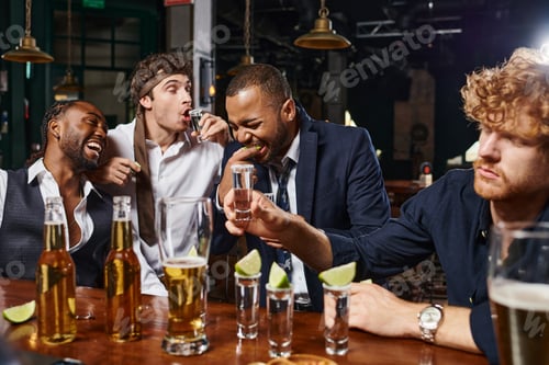 Preview: candid photo of funny and drunk interracial men in formal wear drinking tequila in bar after work