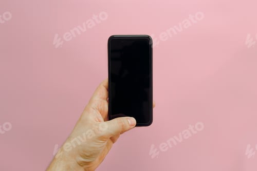 Preview: Hand holding stylish black phone with empty screen on pink background