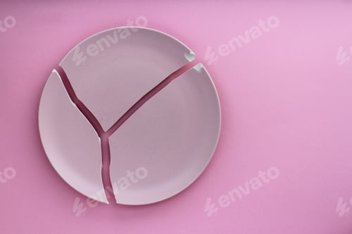 Preview: A broken pink ceramic plate on a gray background. view from above. The concept of diet, old things