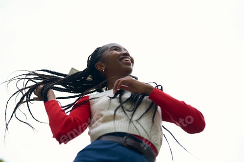 Preview: Young woman smiling joyfully against a bright sky, wearing a red and white sweater. Bruges, Belgium