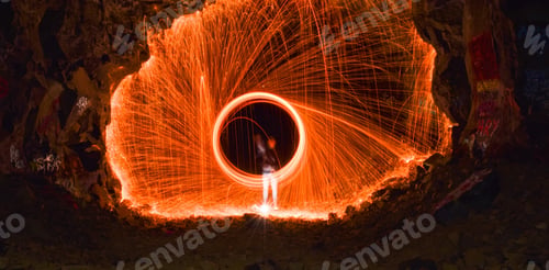Preview: Long exposure shot of a person rotating a burning steel wool in a cave