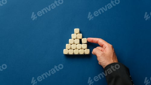 Preview: Business executive building a pyramid shape with wooden dices