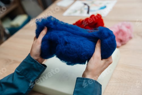 Preview: Hands holding vibrant blue wool fiber during a textile workshop session