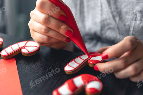 Preview: A woman covers with icing Christmas gingerbread in the form of a candy.