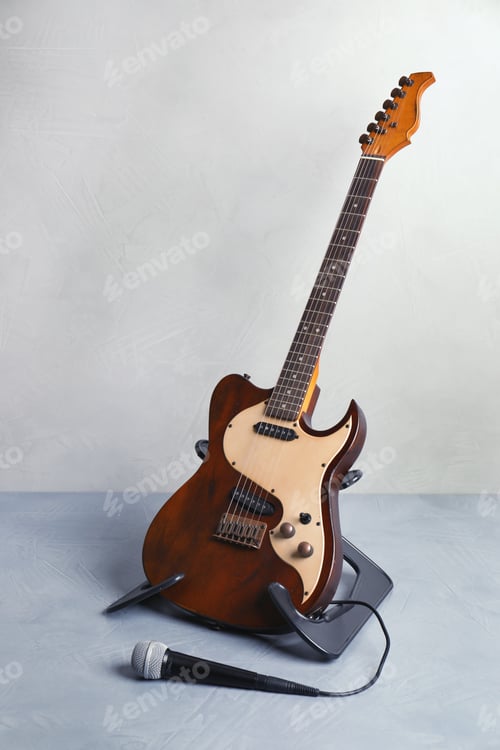 Preview: Stand with modern electric guitar and microphone on floor near color wall