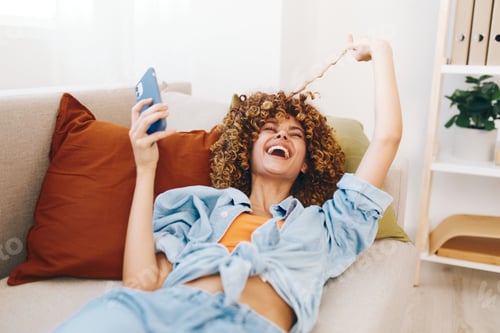 Preview: Laughing Woman Relaxes on Sofa with Phone
