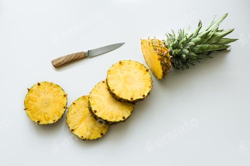 Preview: top view of slices of fresh pineapple with knife isolated on white