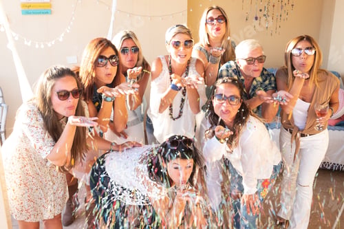 Preview: Group of beautiful girls women blow on confetti celebrating the party. Positive emotion of happiness