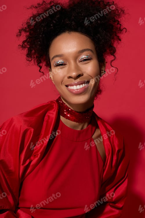 Preview: Joyful young woman in vibrant red attire against a bright pink background radiating happiness