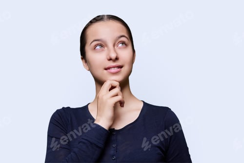 Preview: Pensive teenage female dreamily looking away, white studio background