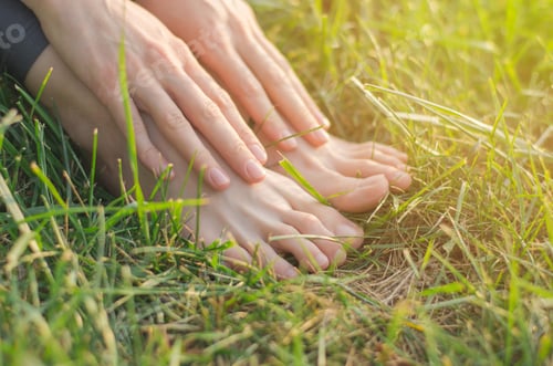 Preview: Barefoot female feet on the green lawn grass close-up