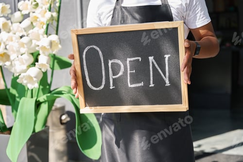 Preview: Signboard open in the hands of a multiracial person