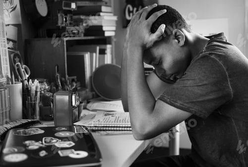 Preview: Teenage boy in a bedroom doing work stressed out and frustrated