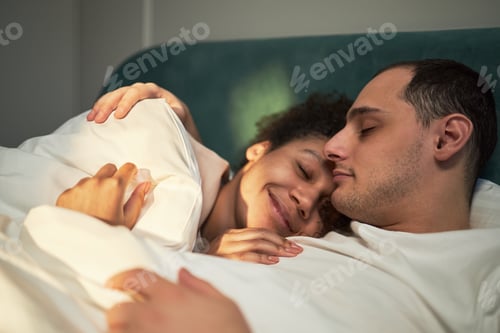 Preview: Young Adult Multiethnic Couple Relaxing Together in Bed Showing Affection